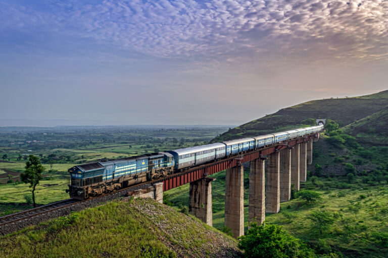 Along with Sunrise, Indian railways long passenger train, exiting a tunnel to cross a tall railway bridge